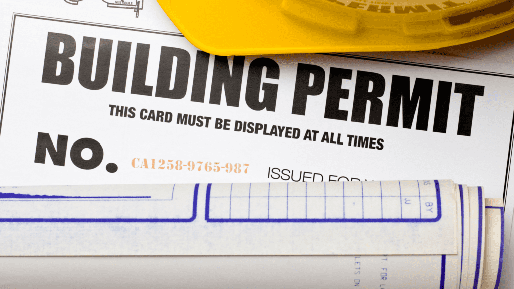 A building permit with blueprints and a hard hat, representing the requirement of a retaining wall permit for construction approval.