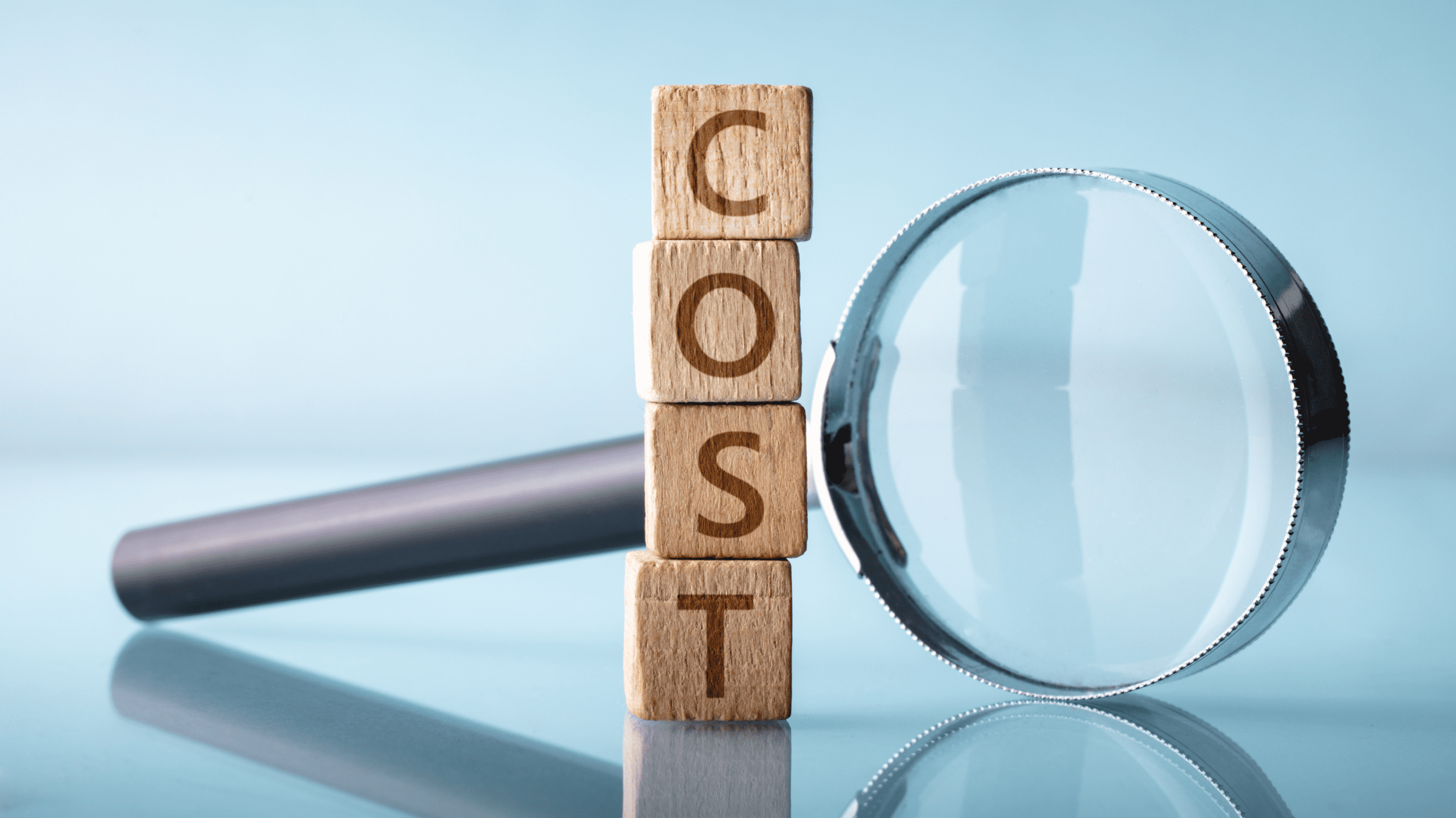 Wooden blocks stacked vertically to spell cost beside a magnifying glass, symbolizing dock installation cost estimates and analysis.