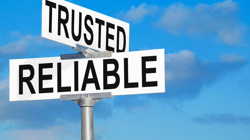 A street signpost with bold words "TRUSTED" and "RELIABLE" against a blue sky, symbolizing dependability in marine construction.